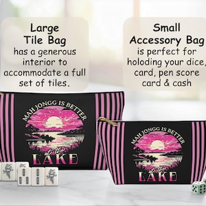 May include: Two zippered Mahjong tile bags, one large and one small, with a black background and pink vertical stripes. The bags feature a sunset lake scene and the text "Mah Jongg is Better at the Lake". Mahjong tiles and dice are also present.