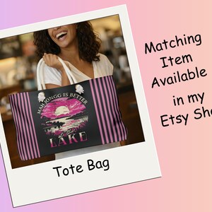 May include: Black tote bag with pink and black vertical stripes and a graphic of a sunset over a lake. Text on the bag reads "Mah Jongg is Better at the Lake". The image also includes the text "Matching Item Available in my Etsy Shop".