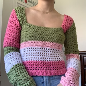 Könnte beinhalten: Ein langärmliges Häkeltop mit quadratischem Ausschnitt. Das Top ist in einem gestreiften Muster aus grünem, rosa und weißem Garn gearbeitet.