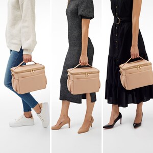 Peut inclure: Un sac &agrave; d&eacute;jeuner isotherme de couleur blush avec des fermetures &eacute;clair et des accessoires dor&eacute;s. Le sac a une poign&eacute;e sup&eacute;rieure et des poches lat&eacute;rales. Le sac est pr&eacute;sent&eacute; port&eacute; par une personne dans diff&eacute;rentes tenues.