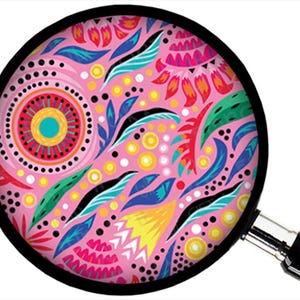 Puede incluir: Un dise&ntilde;o circular rosa con un borde negro se ve a trav&eacute;s de una lupa. El dise&ntilde;o presenta patrones florales y abstractos coloridos en tonos de rosa, rojo, azul, verde, amarillo y negro. La lupa tiene un mango negro y un borde plateado.
