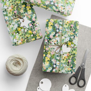 May include: Gift-wrapped presents with floral patterned paper, tied with twine and adorned with white star and heart-shaped tags. A spool of twine, scissors, and blank tags are also visible, suggesting a crafting or gift-giving theme.