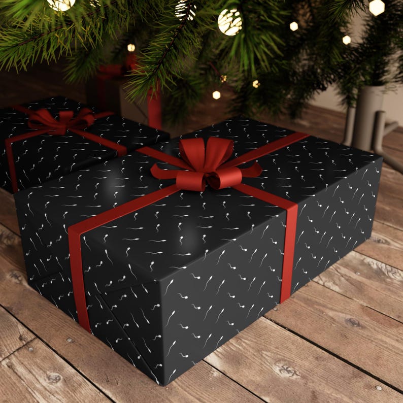 Puede incluir: Dos cajas de regalo rectangulares envueltas en papel negro con un patr&oacute;n blanco repetitivo de peque&ntilde;as formas similares a renacuajos. Cada caja est&aacute; atada con una cinta roja vibrante que forma un lazo decorativo en la parte superior.