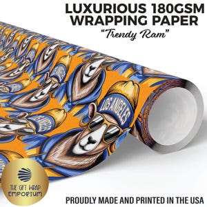 May include: A roll of luxurious 180gsm wrapping paper with a repeating pattern of a cartoon ram wearing sunglasses and a blue beanie with "LOS ANGELES" on it. The background is orange. The text "Trendy Ram" is also visible.