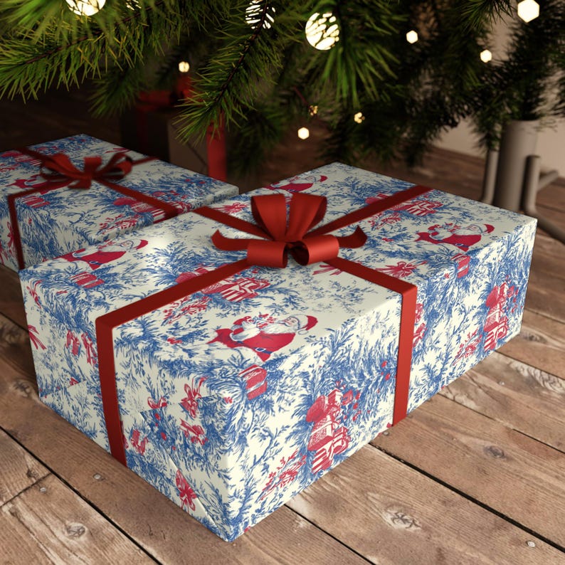May include: Two rectangular gift boxes wrapped in cream-colored paper featuring a blue toile-style pattern of pine branches and red illustrations of Santa Claus. Each box is tied with a smooth, dark red satin ribbon arranged in a cross pattern.
