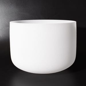 May include: A white, rounded ceramic bowl with a smooth, matte finish. The bowl has a wide opening and a gently curved base. The background is black, providing contrast to the white bowl.