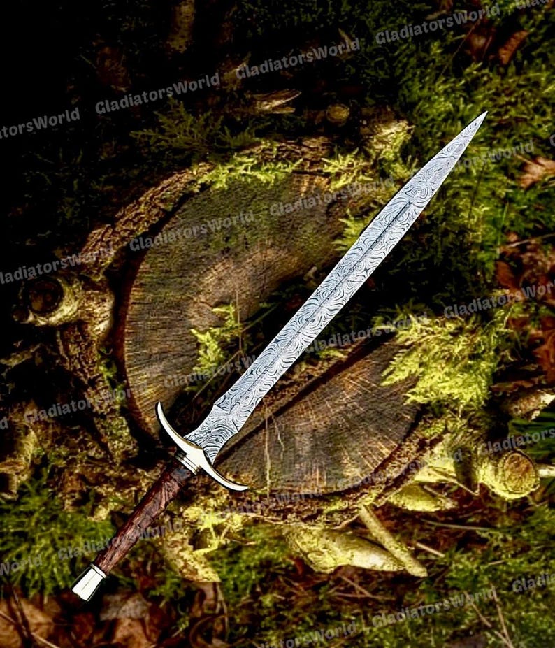 May include: A detailed image of a long, ornate sword with a patterned blade. The hilt features a gold-colored guard and a dark brown handle. The sword rests on a mossy, wooden surface, suggesting a historical or fantasy theme.