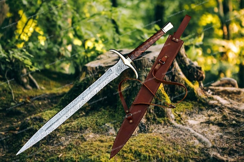 May include: A detailed image of a sword with a patterned blade and a brown wooden handle. The sword is accompanied by a brown leather sheath. The sword is resting on a mossy surface, with a blurred forest background.