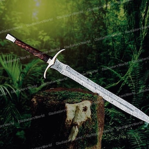 May include: A long, ornate sword with a patterned blade and a dark wooden handle. The hilt is silver-colored with curved quillons. The sword is displayed against a backdrop of lush green foliage.