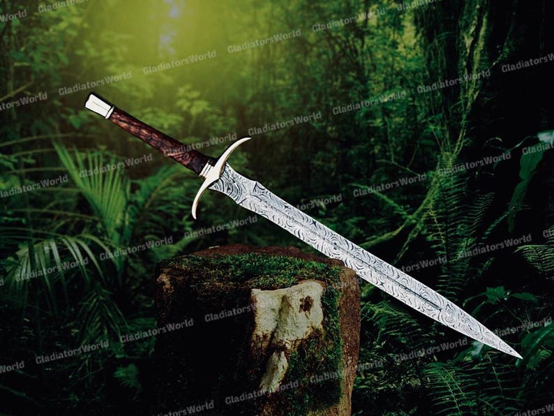 May include: A long, ornate sword with a patterned blade and a dark wooden handle. The hilt is silver-colored with curved quillons. The sword is displayed against a backdrop of lush green foliage.