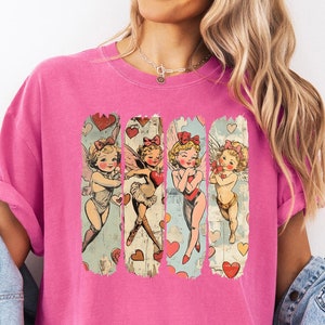 May include: Pink t-shirt with a vintage illustration of four cherubs with hearts and flowers. The illustration is in a distressed style.