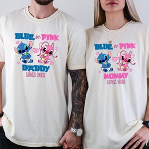 Puede incluir: Dos camisetas de color crema con un gr&aacute;fico de Stitch azul y rosa. El texto en las camisetas dice "Blue or Pink Daddy Loves You" y "Blue or Pink Mommy Loves You".