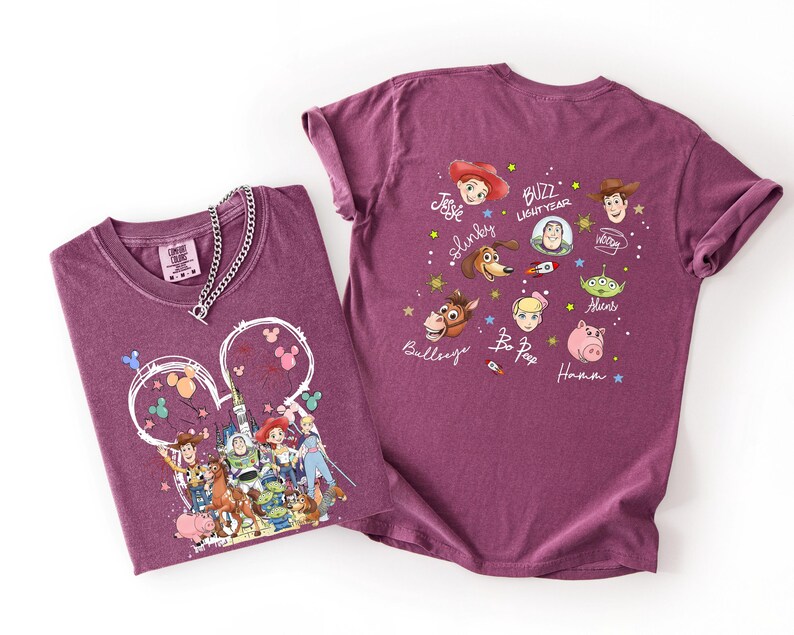 K&ouml;nnte beinhalten: Zwei weinrote T-Shirts mit Toy Story-Charakteren von Disney. Ein Shirt zeigt eine gro&szlig;e Grafik der Charaktere in einer Mickey-Mouse-Kopfkontur. Das andere Shirt hat Charakterportr&auml;ts und Namen. Eine silberne Halskette befindet sich auf einem Shirt.