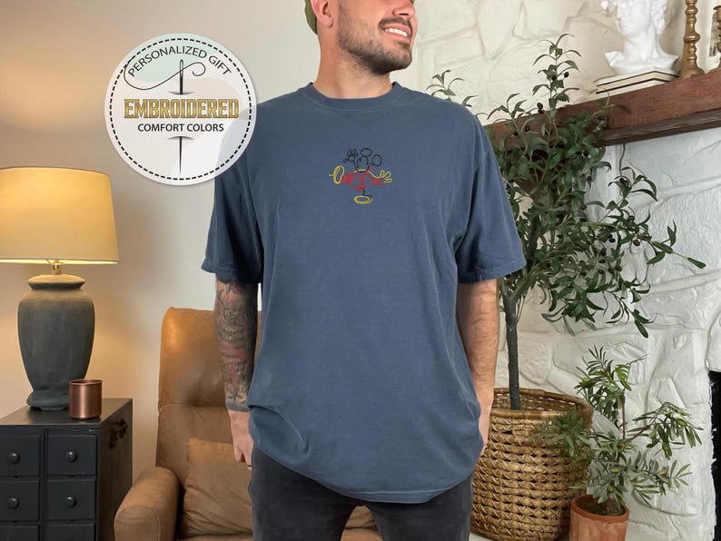 Op de afbeelding: Een marineblauw t-shirt met een geborduurd Mickey Mouse-ontwerp in geel, rood en zwart. Het shirt heeft een ontspannen pasvorm en korte mouwen.