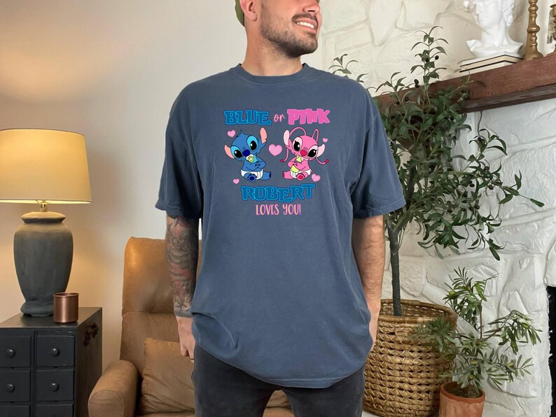 Puede incluir: Una camiseta azul y azul marino con un gr&aacute;fico de Stitch y Angel sosteniendo biberones. El texto en la camiseta dice "Blue or Pink Robert Loves You!"