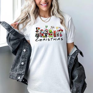 May include: White t-shirt with a graphic of characters from The Nightmare Before Christmas, including Jack Skellington, Sally, and Oogie Boogie. The text "CHRISTMAS" is printed below the characters.