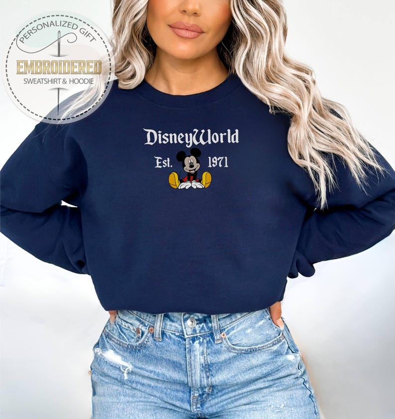 May include: Navy blue sweatshirt featuring the embroidered text "DisneyWorld Est. 1971" and a Mickey Mouse graphic. The sweatshirt is a crew neck style and is a personalized gift.