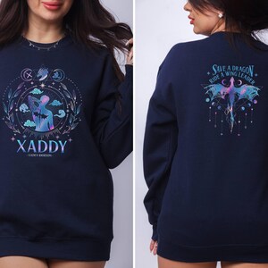 May include: A navy blue sweatshirt with a graphic design on the front and back. The front design features a person with wings and the text "XADDY - XADDY ROBINSON". The back design features a dragon with the text "SAVE A DRAGON - RIDE A WING LEADER".