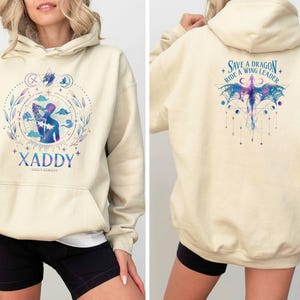 May include: A cream-colored hoodie with a graphic of a person with wings and the text "XADDY" on the front. The back of the hoodie has a graphic of a dragon with the text "Save a Dragon Ride a Wing Leader".