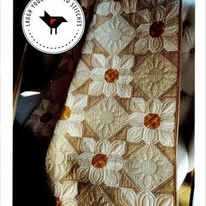 May include: A quilt titled COTTON DAISIES featuring a repeating floral pattern with cream-colored petals and brown centers, set against a brown and white checkered background. Available in sizes: Wall Hanging 45" x 45", Lap 45" x 63", Queen 81" x 99".