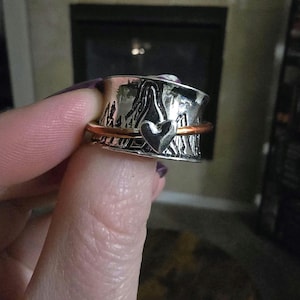May include: A silver ring with a copper band and a heart design. The ring is textured and has a hammered finish.