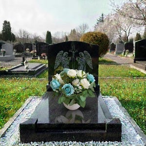 Peut inclure: Une pierre tombale en granit noir avec des anges gravés et une croix, ornée d'un bouquet de roses bleues et blanches dans un vase blanc. La pierre tombale est située dans un cimetière avec d'autres pierres tombales et de l'herbe verte.