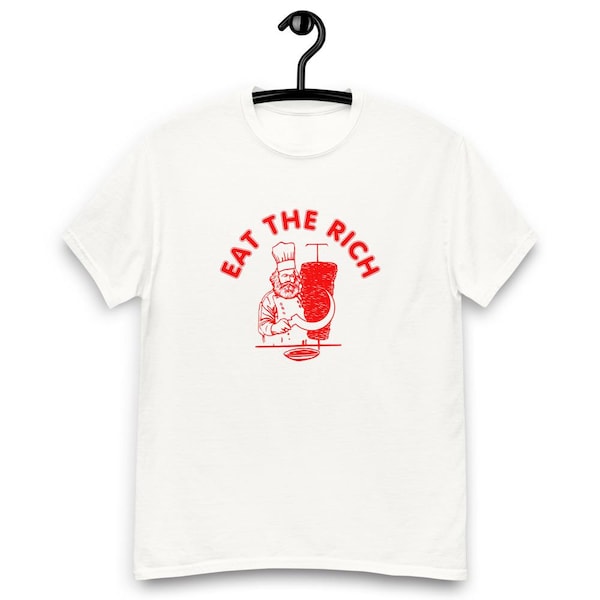 May include: White t-shirt with a red graphic. The graphic features a chef with a beard and chef's hat, holding a curved knife next to a vertical stack of meat. The text "EAT THE RICH" is above the chef.