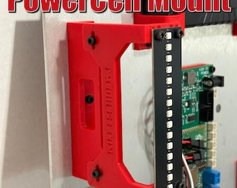 May include: A red PowerCell Mount with the text "PowerCell Mount" in red. The mount is attached to a white surface with black screws. A black circuit board with LED lights is attached to the mount. Logos for Fans.com, GPSTAR, and Ninja Tunes are visible.