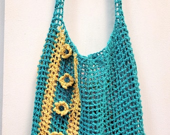May include: A teal and yellow crocheted tote bag with a decorative flower design. The bag has a long strap and is made of a lightweight, open-weave material.