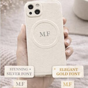 May include: Cream-colored phone case with a textured finish, featuring the initials "M.F." in a silver font within a circular design. The case has a camera module and is shown with text that says "Customize Your Initials."