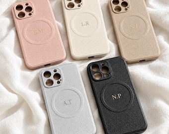 May include: Five textured phone cases with circular magnetic charging rings and gold-embossed initials. The cases are coloured pink, cream, tan, light grey, and black, each featuring a camera cutout array and precise port openings at the bottom.