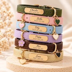 May include: A stack of six textured leather pet collars in olive green, pink, light blue, lavender, brown, and gold. Each collar features a gold-tone metal nameplate engraved with a name and phone number, plus a small dangling charm.