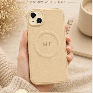 May include: A beige leather phone case with the initials "M.F" embossed on the back. The case is designed to be personalized and features the text "PERSONALIZED LEATHER PHONE CASE" and "CUSTOMIZE YOUR INITIALS".