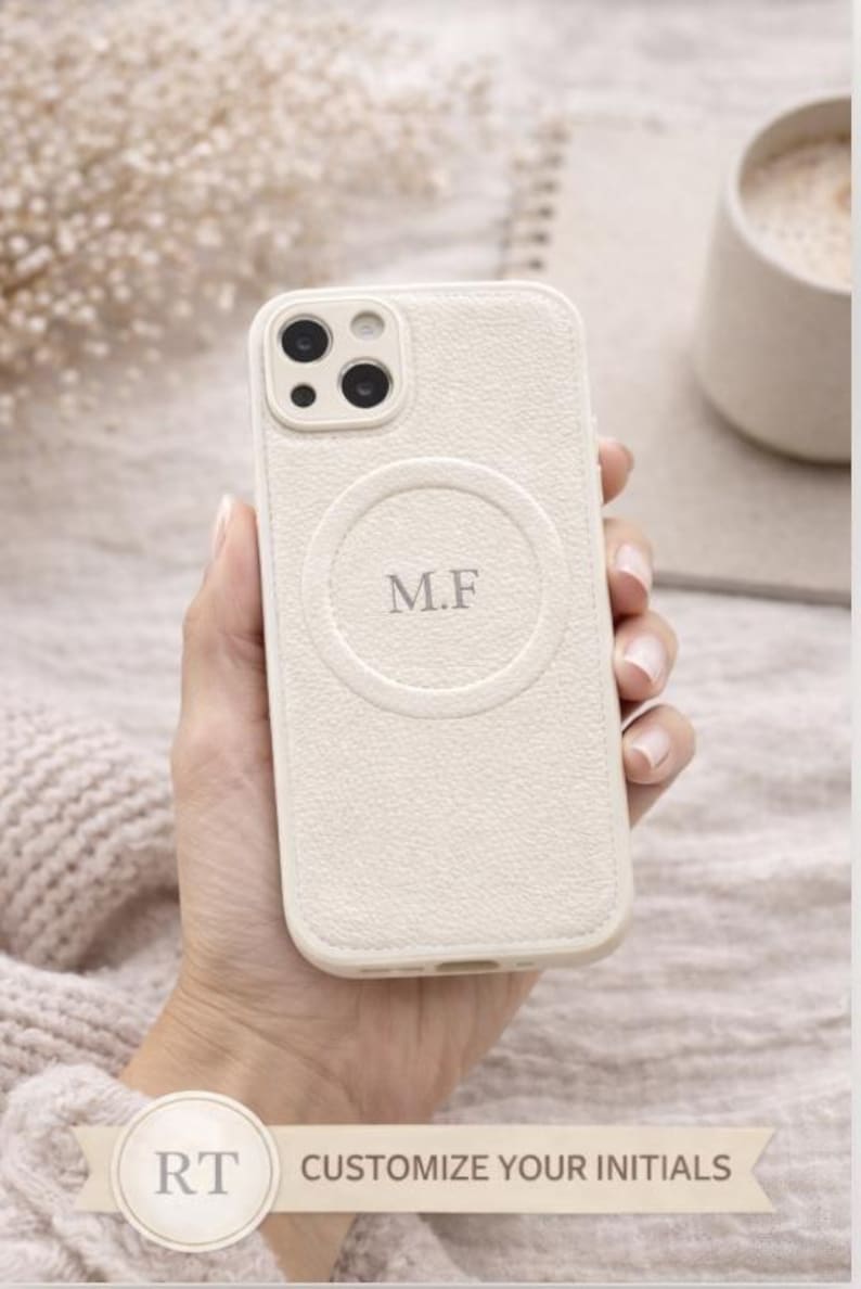 May include: Cream-colored phone case with a textured finish, featuring a circular design with the initials "M.F." The case has a camera cutout and is held in a hand. The text "CUSTOMIZE YOUR INITIALS" is at the bottom.