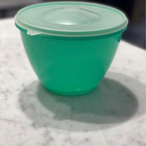 Puede incluir: Una taza de cerámica blanca con un asa negra y el texto "But First, Coffee" en un estilo manuscrito. La taza está sobre una superficie blanca. La taza mide aproximadamente 10 cm de alto.