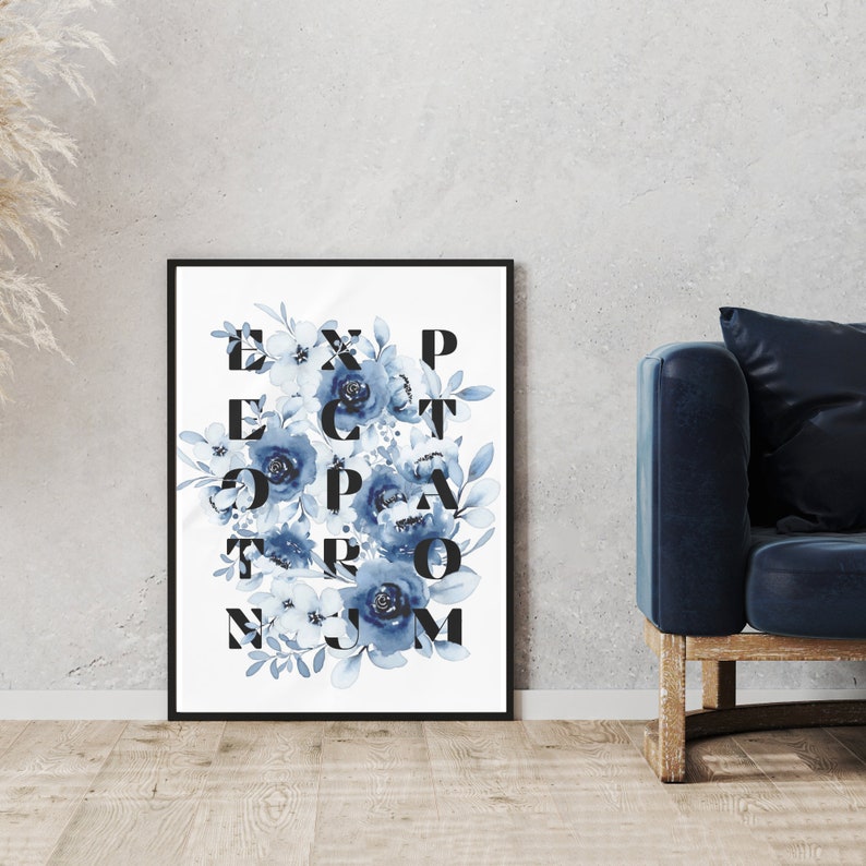 May include: A black framed print with a white background and blue watercolor flowers. The flowers are arranged in a grid pattern with the letters "EXPECT THE UNEXPECTED" spelled out in black.