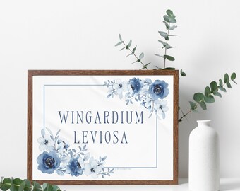 May include: A framed print with a watercolor design of blue flowers and the text "Wingardium Leviosa" in a dark blue font.