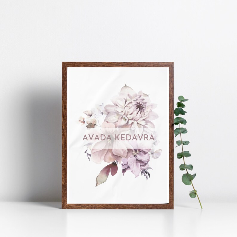 May include: A framed print with a watercolor painting of a bouquet of pink and purple flowers. The text "AVADA KEDAVRA" is printed in a light pink font on the print.