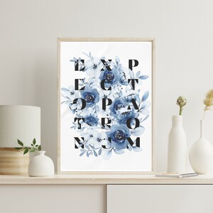 May include: A framed print with a white background and blue watercolour flowers. The flowers are arranged to spell out the words "Expect the Extraordinary".
