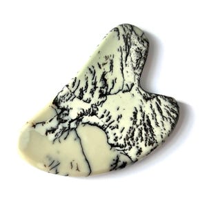 May include: A cream-colored, teardrop-shaped stone with a handle. The stone features intricate black veining patterns throughout, creating a unique, natural design. The smooth, polished surface reflects light, highlighting the contrasting colors and textures.