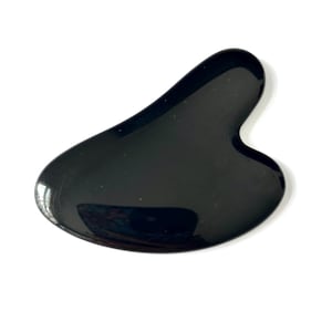 May include: A black gua sha tool with a smooth, curved design. The tool is made of a shiny, reflective material and is designed for facial massage and skincare routines. The shape is ergonomic, with rounded edges and a heart-like curve.