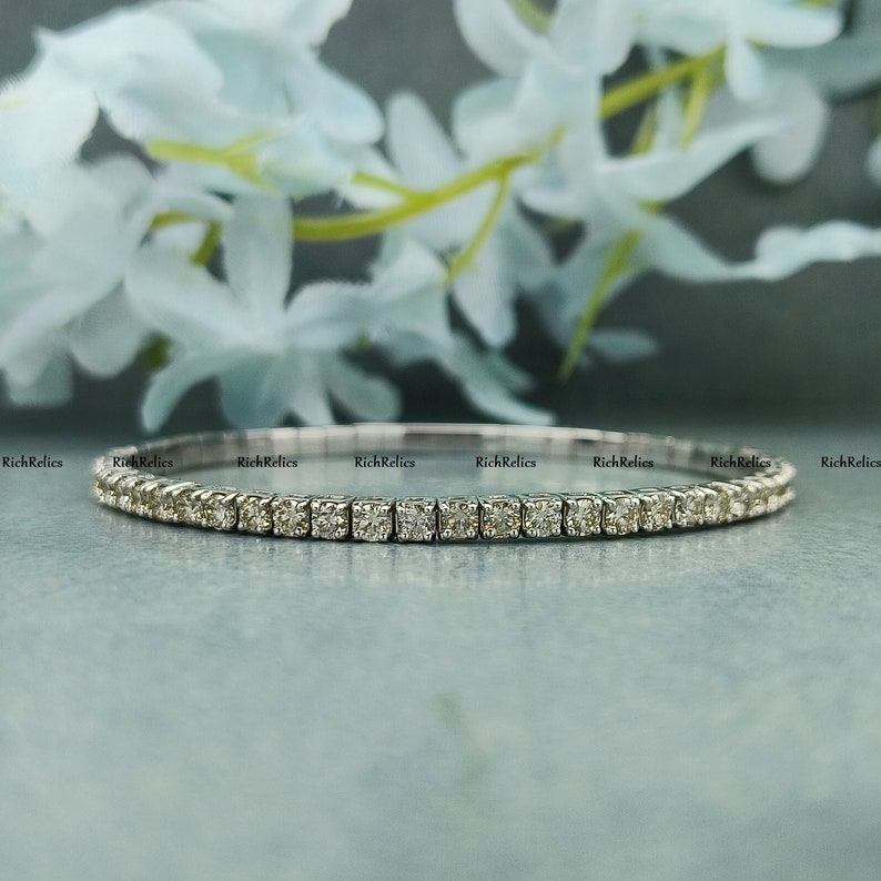 K&ouml;nnte beinhalten: Ein zartes Silberarmband mit einer Reihe kleiner, quadratischer Diamanten. Das Armband ist schlicht und elegant und perfekt f&uuml;r den Alltag.