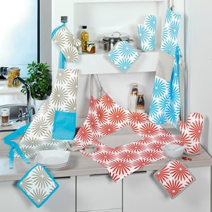 Puede incluir: Un conjunto de accesorios de cocina con un patrón floral en tonos azules, rojos y grises. El conjunto incluye agarraderas, guantes para horno y un delantal.