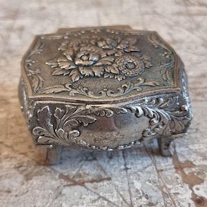 Boîte en métal vintage Cette magnifique boîte en métal de style renaissance est magnifiquement gaufrée et décorée de fleurs.