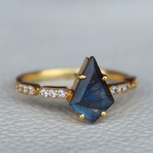 May include: A gold ring with a dark blue gemstone and a band of small diamonds.