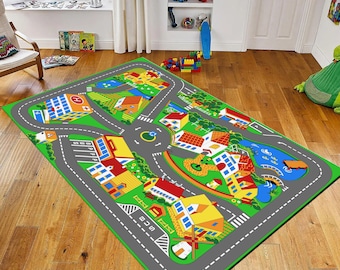 May include: A colorful play rug featuring a town layout with roads, buildings, and a roundabout. The rug has a green border and includes a hospital, houses, and a lake. The roads are gray with white lines, and the buildings are various colors.