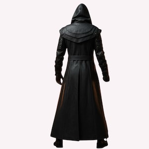 May include: A long, black leather coat with a hood, belt, and decorative shoulder accents. The coat has a full-length design and is shown from the back. The sleeves have decorative details near the wrists. The coat is made of a smooth, dark material.