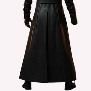 May include: A long, black leather coat with a flared skirt, visible from the waist down. The coat features a center pleat and is paired with black gloves and boots. The image is shot from the waist down.