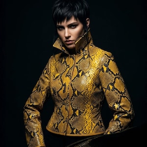Könnte beinhalten: Eine taillierte Jacke mit gelb-schwarzem Schlangenmuster. Sie hat einen hohen Kragen und einen Reißverschluss. Das Design der Jacke ist modern und tailliert. Der dunkle Hintergrund hebt die Farben und die Textur der Jacke hervor.