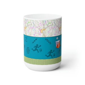 May include: White ceramic mug with a blue and green design. The design features a map with numbers and lines, and two figures running with compasses. The text "5" is visible on the mug.